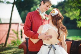 groom wearing red sweater and bride with backless dress with purple belt and butterfly headpiece